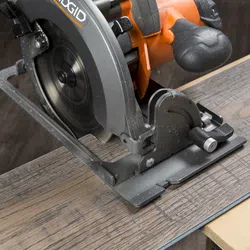 Close-up of a Ridgid circular saw cutting through a piece of wood with visible motion blur on the blade.