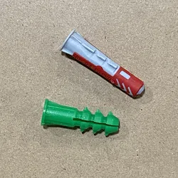 Two plastic wall anchors, one red and white and one solid green, on a textured beige surface.