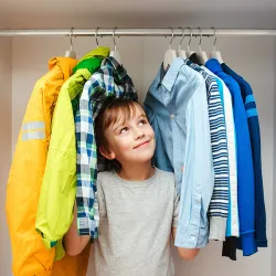 a boy standing in front of a rack of clothes