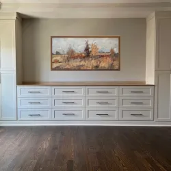 a room with white cabinets and a painting on the wall