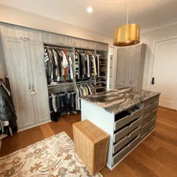 Install custom closet. Minroom with a shelf and a table with clothes on it