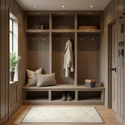 Cozy mudroom with built-in bench, hooks, storage cubbies, beige walls, cushions, and a window with plant.