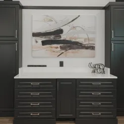 Modern black kitchen cabinets with white countertop, abstract wall art, and decorative sculpture with potted plant.