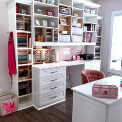 custom craft room with white drawers, shelves, desk, island, scrapbooking supplies, crafting supplies, a salmon chair and hardwood flooring
