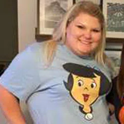 Smiling woman wearing a light blue shirt featuring a cartoon character from The Jetsons.