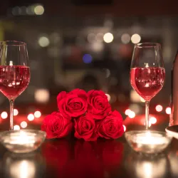 a group of wine glasses with red roses in them