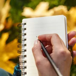 a person holding a pen and a notebook