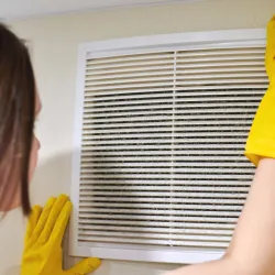 a woman looking at a dusty air vent