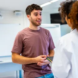 Young man talking to a female doctor in a bright medical office during a consultation session.