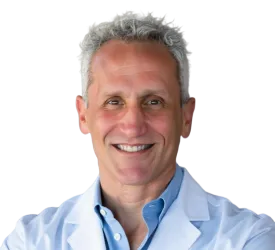 Smiling middle-aged male doctor with gray hair wearing a white coat and light blue shirt against a clear background