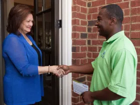 A woman and a man greet each other by shaking hands.