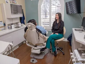 Dentist consulting with patient in a modern dental office with natural light from arched window.