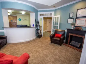 Reception area of Volner Family Dentistry with seating, front desk, certificates, and calming blue walls.