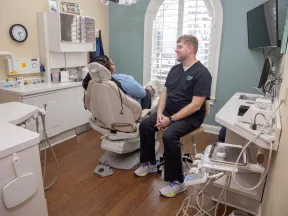Dentist consulting a patient in a modern dental office with a dental chair and equipment.