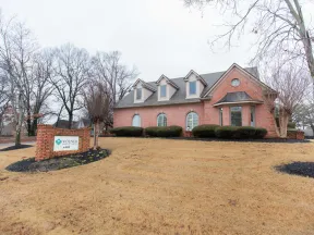 Brick office building with manicured shrubbery and a sign for Volner Insurance on a overcast day