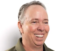 Smiling middle-aged man with curly hair wearing a green shirt against a white background