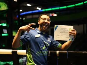 Happy employee holding Employee of the Month certificate, celebrating at a vibrant indoor sports venue.