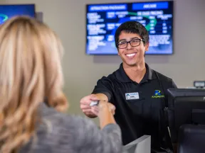 A smiling employee assists a customer at a service desk, showcasing friendly customer service.
