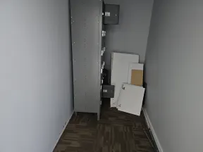 Narrow room with gray walls, a storage cabinet, and miscellaneous panels and boards leaning against the wall.
