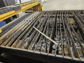 Industrial metal cutting table with steel slats and metal debris in a factory setting