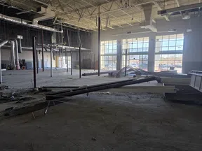 Interior of large commercial building under construction with exposed beams and unfinished floors during daytime.