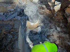 Construction workers demolishing an old concrete pool with heavy machinery and tools in a backyard.