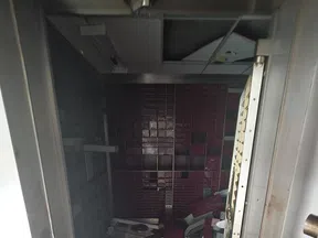 Interior view of a dark, cluttered safe room with open heavy metal door and scattered debris on the floor.