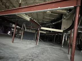 Empty industrial interior with exposed ceiling, metal beams, and scattered construction materials on concrete floor