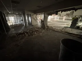 Dimly lit interior of a building under demolition with debris and exposed structural elements.
