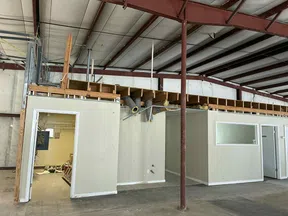 Interior of an unfinished industrial space with white partition walls and exposed ceiling beams