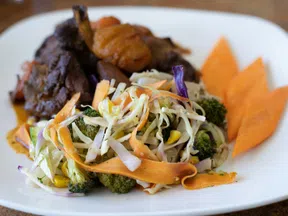 Plate of cooked meat with steamed vegetables including shredded cabbage, carrots, broccoli, and sliced sweet potatoes.