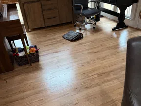 Modern home office with wooden floor, desk, computer setup, office chair, and basket with toys near window.