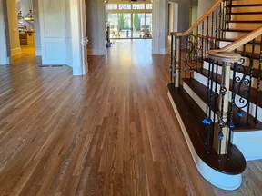Spacious entryway with curved wooden staircase, wrought iron balusters, hardwood floors, and large open layout.