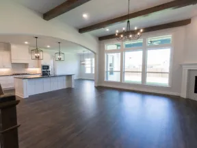 Spacious modern open-concept living room and kitchen with dark wood floors, large windows, and white cabinetry.