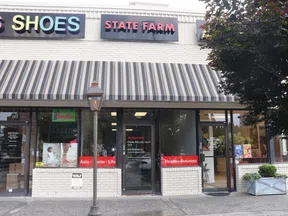 Strip mall storefronts featuring State Farm insurance office and Kids Shoes shop under a striped awning with street lamp.