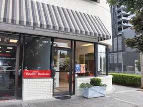 State Farm office entrance with striped awning, health and business sign, next to Rosy Alterations shop window.
