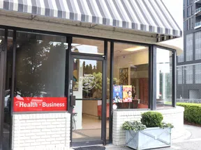 Street view of Rosy Alterations shop with striped awning, glass door, and window displays in urban setting.
