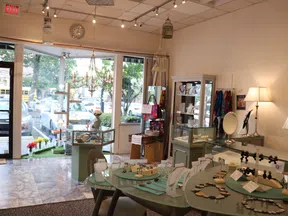 Bright jewelry store interior with display cases, necklaces, earrings, and decorative lighting near glass storefront.