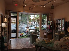 Jewelry store interior with display cases, chandelier, and large windows showing parked cars outside on a sunny day