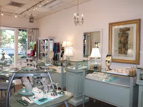 Interior of a bright jewelry store with glass display cases showcasing rings, necklaces, and bracelets.