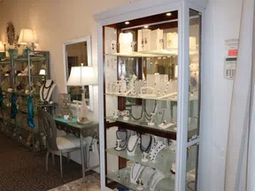 Brightly lit glass display cases filled with various necklaces and jewelry in an elegant boutique.