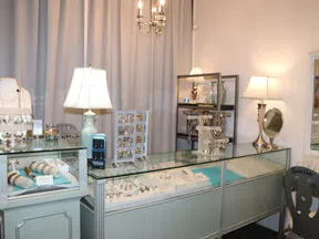 Jewelry store display with bracelets, rings, earrings in glass cases and soft lighting lamps.
