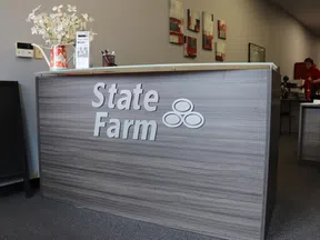 Modern State Farm office reception desk with logo, flower vase, brochures, and wall art in a professional setting.