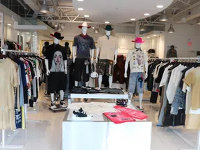 Modern clothing store interior with mannequins dressed in casual attire and racks of various apparel.