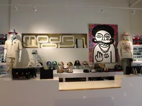 Modern fashion store interior with mannequins, graphic art, and various hats displayed on white shelves.