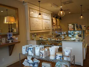 Cozy bakery interior with display cases of pies, packaged goods, warm lighting, and Southern Baked signage