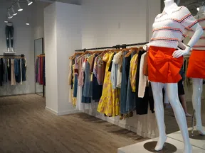 Modern clothing store interior with colorful dresses on racks and a mannequin in a red skirt and striped top