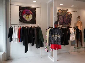 Clothing store interior with hanging racks of colorful apparel and artistic wall murals in a bright space