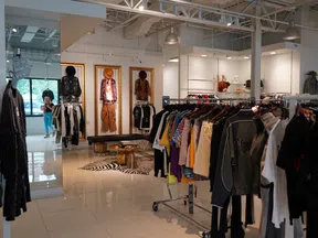 Modern clothing store interior with racks of colorful apparel and mannequins against white walls and tiled floor.