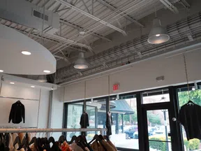 Modern clothing store interior with black shirts hanging on racks and natural light from large windows